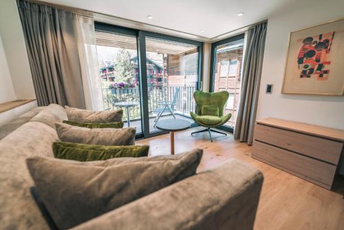 a living room with a couch and chairs and windows at Hotel Eden Wellness in Zermatt
