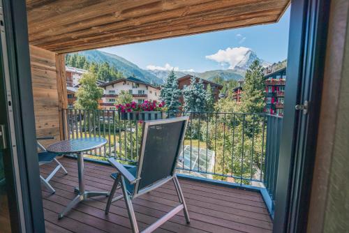 a balcony with a table and chairs and a view at Hotel Eden Wellness in Zermatt
