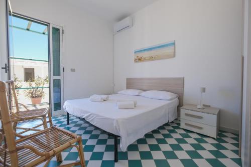 a bedroom with a bed and a chair and a window at Sea View Penthouse-Attico in Baia Verde