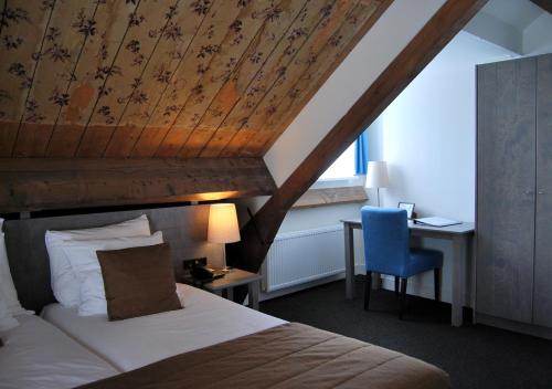 a bedroom with a bed and a desk with a blue chair at Bitter en Zoet in Veenhuizen