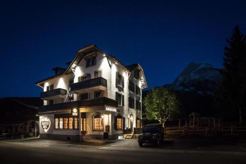 a large white building with lights on at night at Hotel Bären in Gsteig