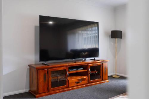 a flat screen tv sitting on top of a wooden entertainment center at Ignatius Retreat - Family Entertainer, Serene View in Kelso