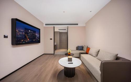a living room with a couch and a tv on a wall at 威海市区威高广场万信至格酒店 in Weihai