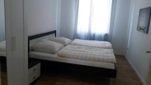 a bedroom with a bed with white sheets and a window at Eulennest-lu in Ludwigshafen am Rhein