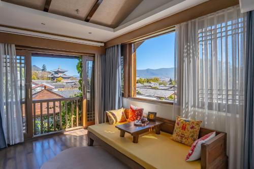 a living room with a couch and a large window at 指云公馆Lijiang Mufu Royal Garden Resort半山观景民宿 in Lijiang