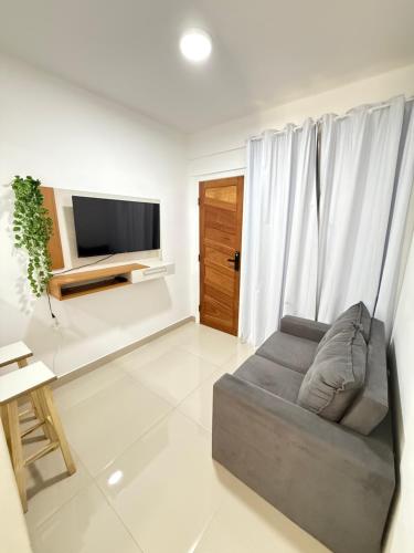 a living room with a couch and a flat screen tv at Apartamento Praia Jacaraípe in Serra