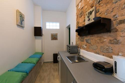 a kitchen with a sink and a counter with green cushions at Xenones Lindos in Líndos