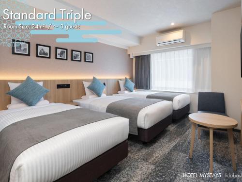 a hotel room with two beds and a table at HOTEL MYSTAYS Iidabashi in Tokyo