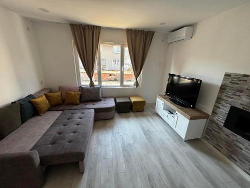 a living room with a couch and a flat screen tv at АпартаменЪТ у Град in Belogradchik
