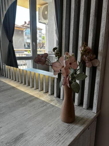 a vase with flowers in it sitting on a porch at АпартаменЪТ у Град in Belogradchik