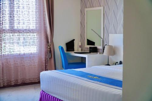 a bedroom with a bed and a desk and a mirror at The Mira Boutique Hotel in Thu Dau Mot