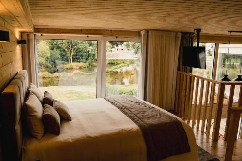 a bedroom with a bed and a large window at Apartamentos Herança do Vez in Arcos de Valdevez