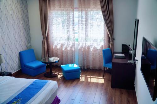 a bedroom with a bed and blue chairs and a window at The Mira Boutique Hotel in Thu Dau Mot
