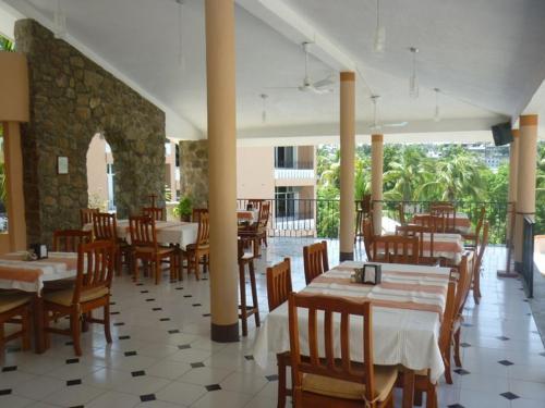 un restaurante con mesas y sillas de madera y una habitación en Hotel Barlovento en Puerto Escondido