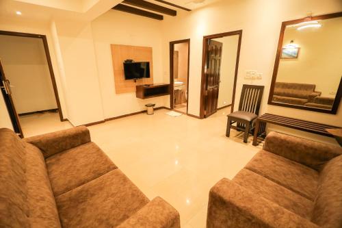 a living room with a couch and a television at Hotel Plaza Heights by RAK Rooms, Mangaluru in Mangalore