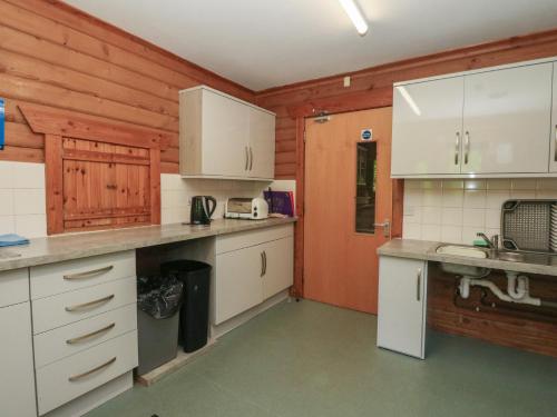 a kitchen with wooden walls and white cabinets at Shore Lodge Brodick Castle in Brodick