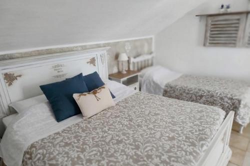 a white bedroom with two beds with blue pillows at Grotta dei Puntali B&B in Carini