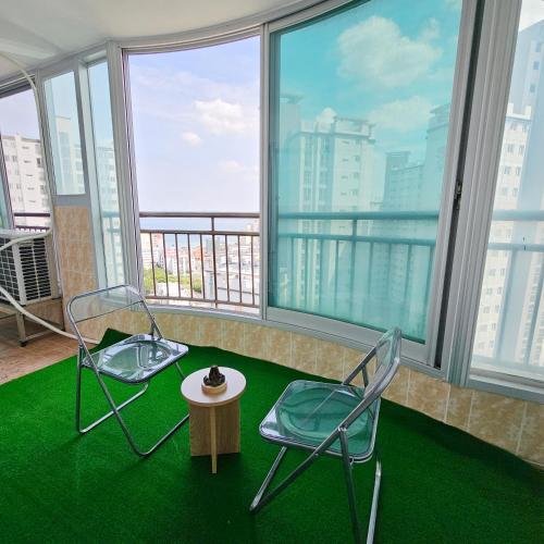 two chairs and a table in a room with large windows at Ocean House PH in Pohang