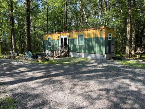 a green and yellow tiny house in the woods at Camptel Poconos in Albrightsville