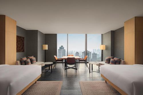 ein Hotelzimmer mit einem Tisch und Stühlen und einem Fenster in der Unterkunft Park Hyatt Jakarta in Jakarta