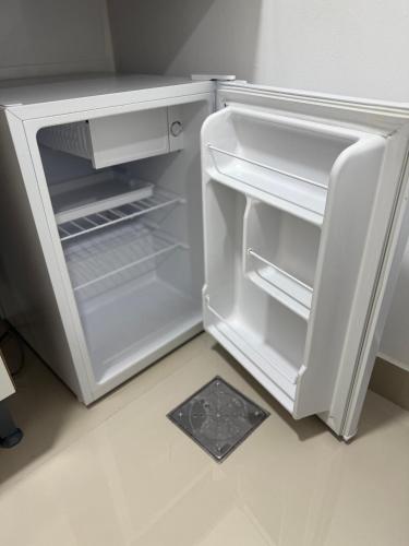 an empty refrigerator with its door open in a kitchen at Apartamento Praia Jacaraípe in Serra