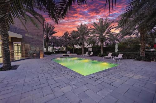 a swimming pool in a courtyard with palm trees at Villa 371 - Al Ghadeer in Ghantoot