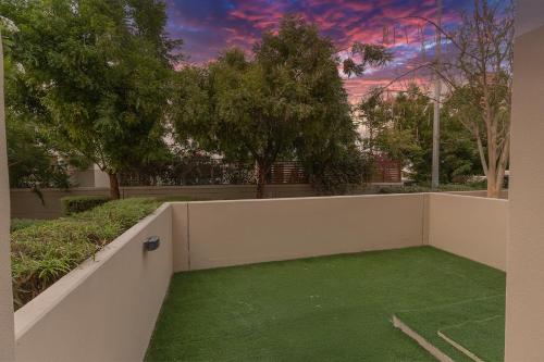 a backyard with green grass and a wall at Villa 371 - Al Ghadeer in Ghantoot