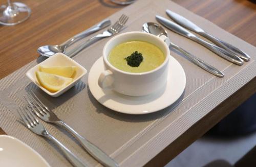 a cup of soup with a piece of broccoli on a table at Great Homes in Kira