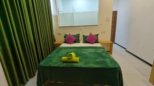 a room with a bed with a green blanket and pink pillows at Riverline Resort Kandy in Kandy