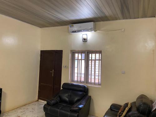 a living room with a leather chair and a ceiling at Luxury 2Bedrooms Retreat Serenity in the City in Enugu Airport