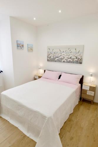 a white bedroom with a large white bed with pink pillows at ValeVacanze in Savona