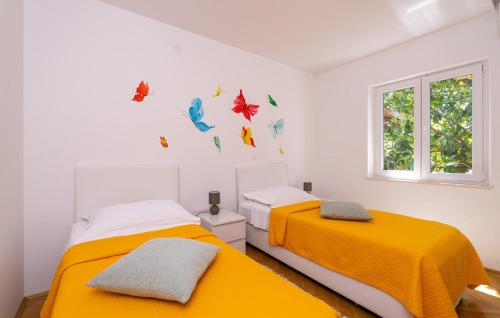 zwei Betten in einem Schlafzimmer mit gelben Laken und Schmetterlingen an der Wand in der Unterkunft Villa None Kate by Villas Guide in Dubrovnik