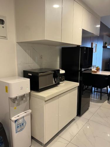 a kitchen with white cabinets and a black refrigerator at Apartemen SkyHouse 3 BR Duxton 16th Floor in Samporo