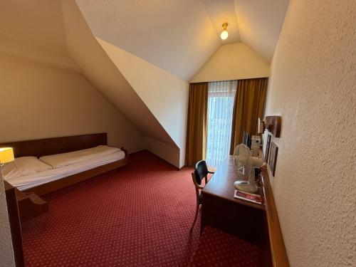a hotel room with a bed and a desk and a window at Hotel Post Viernheim in Viernheim