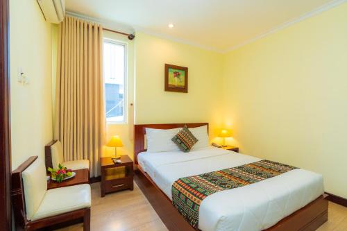 a bedroom with a bed and a chair and a window at Hoang Ha Boutique Hotel in Ho Chi Minh City