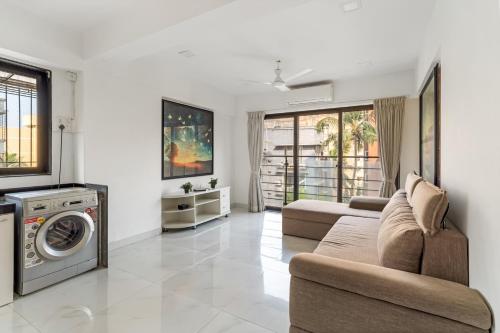 a living room with a couch and a washing machine at Athena 2BHK Khar W by The Bombay Home Company in Mumbai
