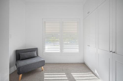 a chair in a white room with a window at Norman's Rest Wagga in Wagga Wagga