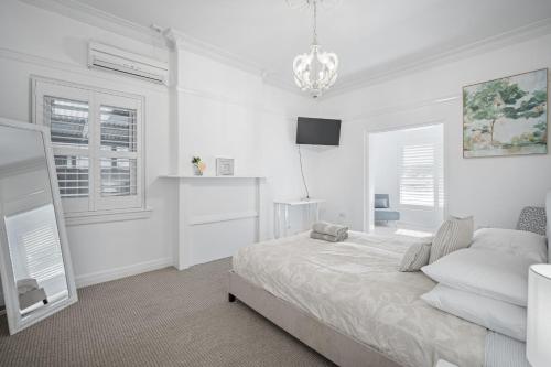 a white bedroom with a bed and a chandelier at Norman's Rest Wagga in Wagga Wagga