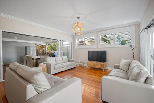 a living room with two white couches and a television at Norman's Rest Wagga in Wagga Wagga