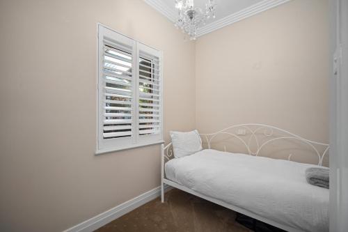 a white bedroom with a bed and a window at Norman's Rest Wagga in Wagga Wagga