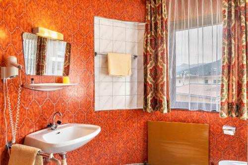 a bathroom with a sink and a mirror and a window at Pension Heidelberg in Hopfgarten im Brixental
