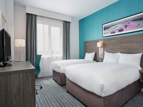 a hotel room with two beds and a television at Leonardo Hotel Southampton in Southampton