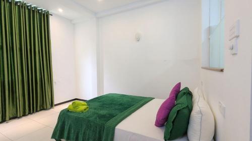 a room with a bed with a green blanket on it at Riverline Resort Kandy in Kandy