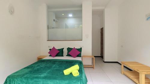 a bedroom with a bed with green sheets and pink pillows at Riverline Resort Kandy in Kandy