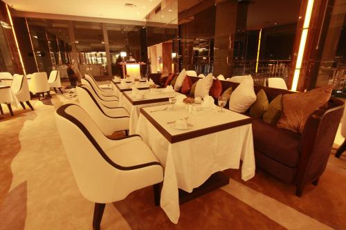 un comedor con mesas blancas y un sofá en Royal Asnof Hotel Pekanbaru, en Pekanbaru