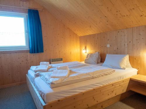 a large bed in a wooden room with a window at Woody Park Feriendorf Murau in Murau