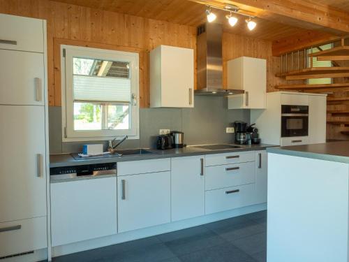 a kitchen with white cabinets and a window at Woody Park Feriendorf Murau in Murau