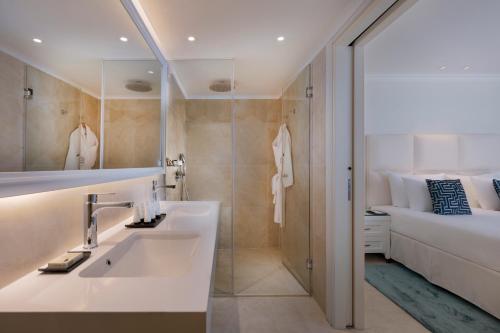 a bathroom with a sink and a shower and a bed at Herbert Samuel Milos Dead Sea in Ein Bokek