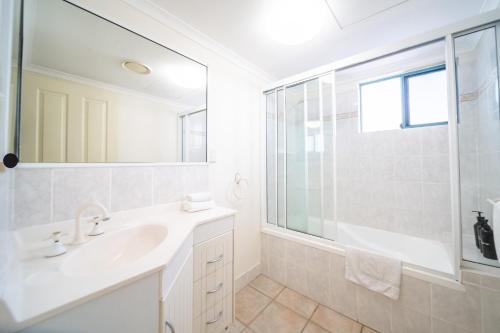 a white bathroom with a sink and a shower at Beachfront Unit on The Strand in Townsville