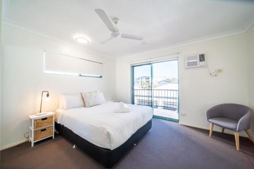 a bedroom with a bed and a chair and a window at Beachfront Unit on The Strand in Townsville